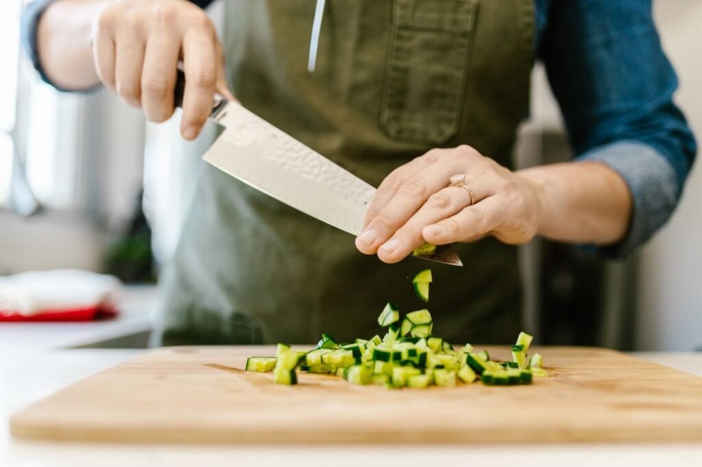 Close-up of a chef slicing cucumbers on a wooden board with precision.