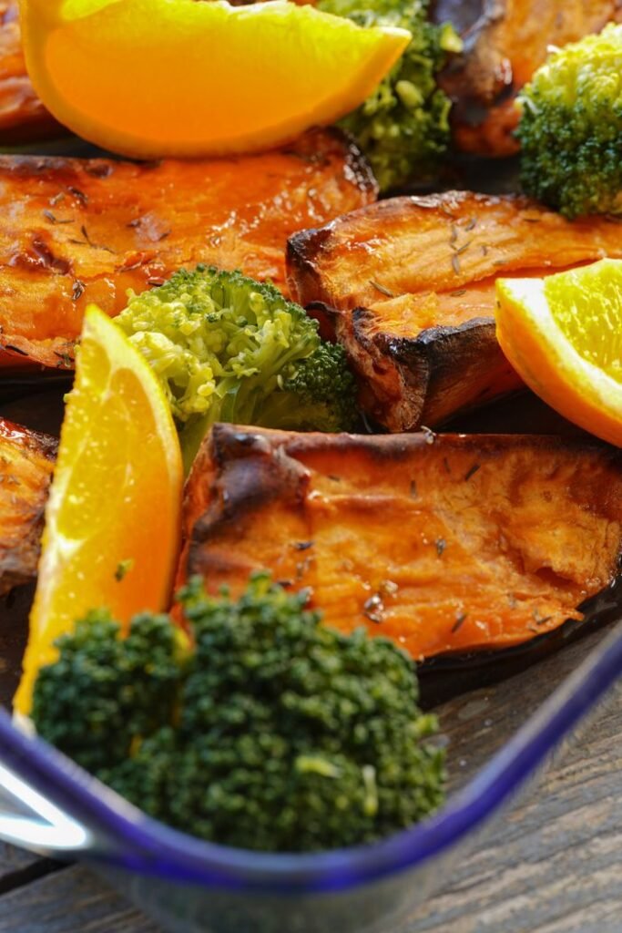 Delicious roasted sweet potatoes with broccoli and orange slices, a vibrant and healthy dish.