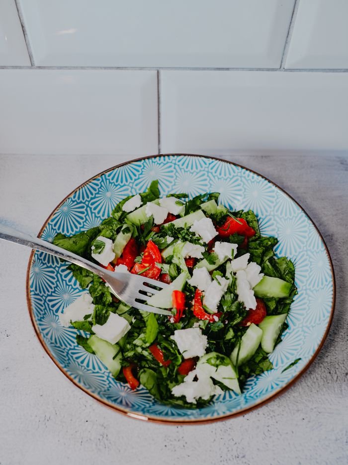 Colorful Greek salad with fresh ingredients and feta cheese in a decorative bowl.
